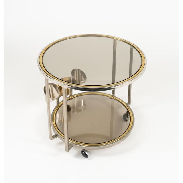 Midcentury amazing three-wheeled round serving bar cart in brass, chrome and smoked glass with Bottle Holder. Made in...