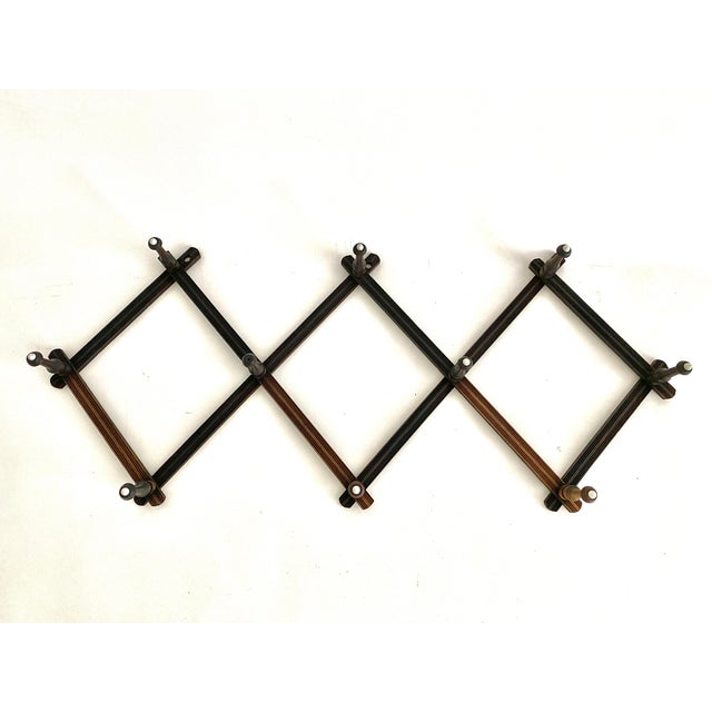 This Art Deco period expandable wall mounted coat/hat rack with 10 pegs features a ribbed detail to the wood with white...