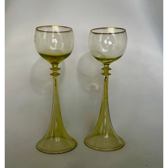 An elegant pair of antique römer wine glasses in delicate pistachio-green glass, with rounded bowls poised above...