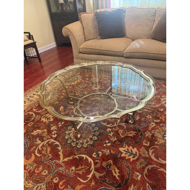 LaBarge hand-cast solid-brass oval cocktail table with a scalloped or piecrust-edge frame, inset clear glass top, curved...