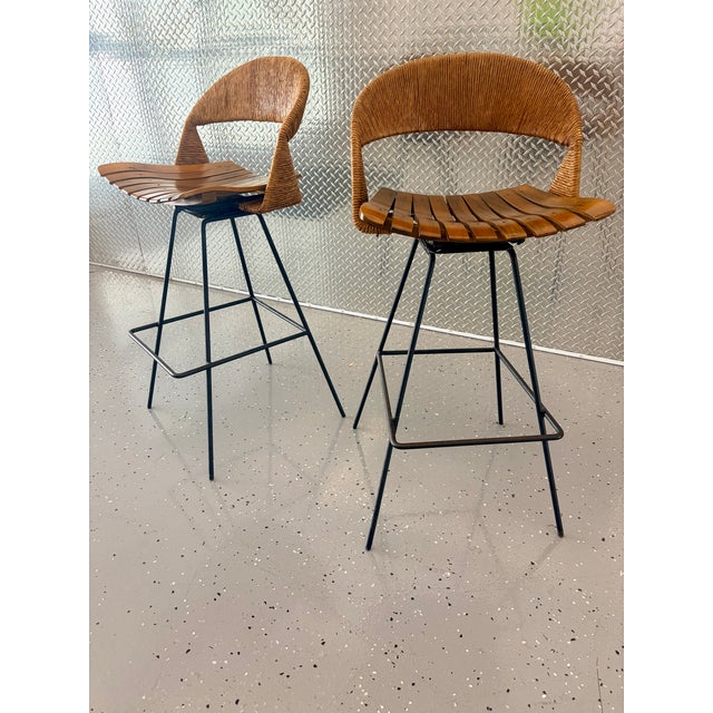 Two rare rotating, counter height stools by Arthur Umanoff. These stools are thoughtfully crafted with a steel frame,...
