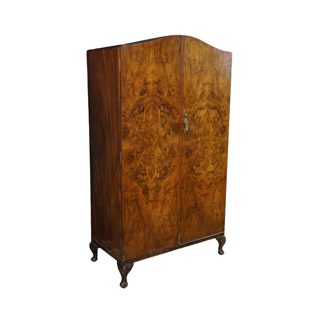 This English Art Deco walnut armoire features a striking, book-matched burr walnut veneer facade that displays a...