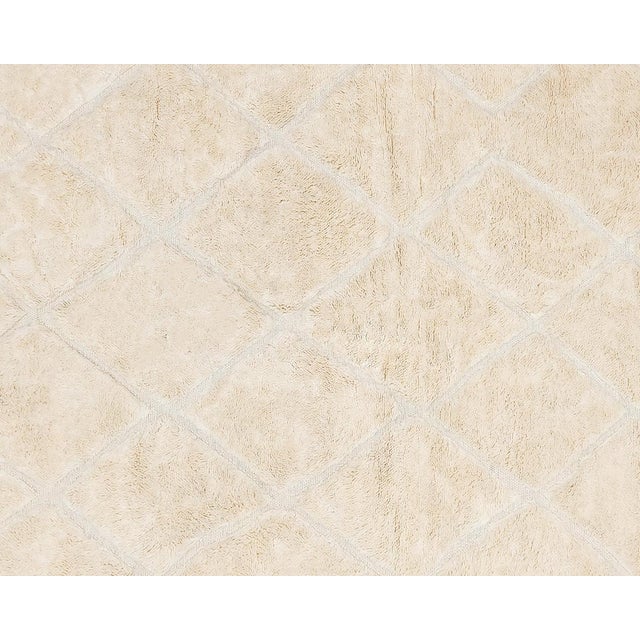 A modern plush hand-knotted wool rug in Off-white Neutral Color, featuring a subtle diamond lattice design that softly...