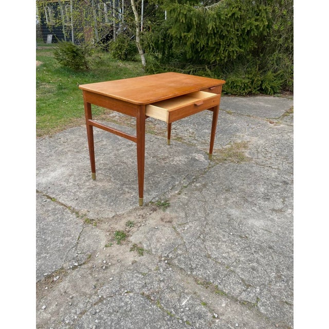 Teak and teak veneer, two drawers in the frame with pull handles in teak veneered bentwood, brass footrests, the chair in...