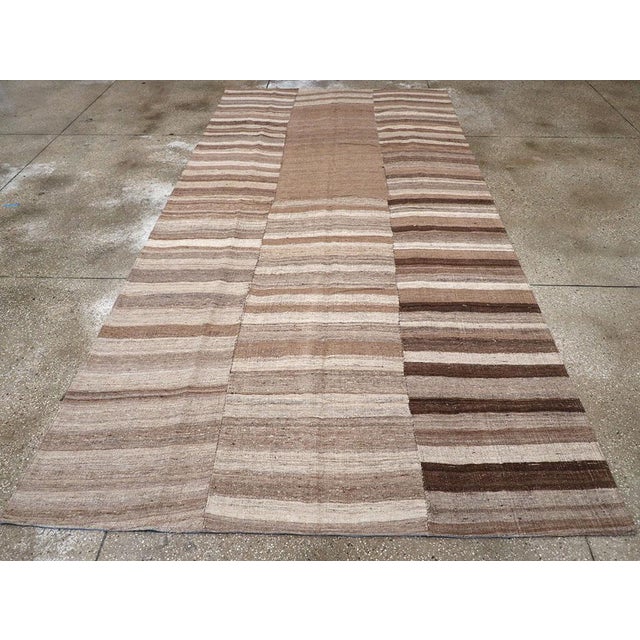 This mid-20th century Turkish flatweave kilim rug, presents a bold and organic aesthetic through its use of natural tones...