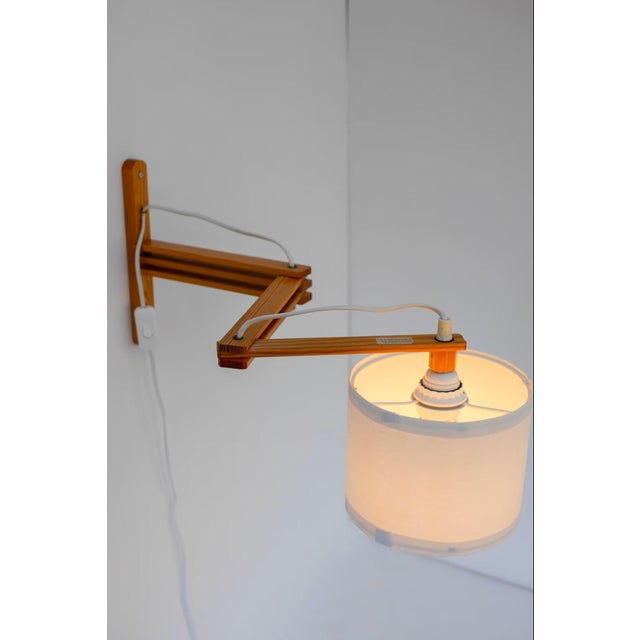 A classic mid-century modern scandinavian accordion wall lamp with a folding swing arm from ikea, crafted in pine and...