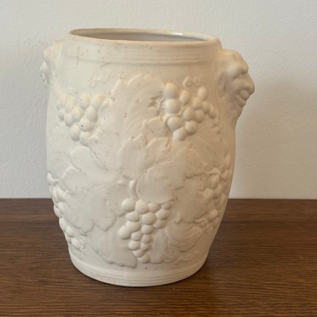 A Hartstone Pottery Bacchus white ceramic bisque wine cooler or vase featuring grape relief detailing and satyr mask...