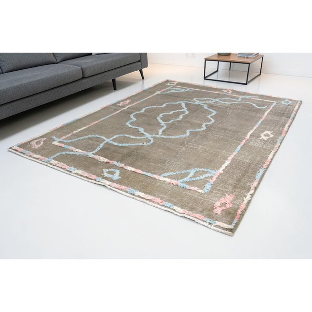 This is a vintage Turkish Oushak rug from the Mid 20th Century. The piece was hand-knotted.