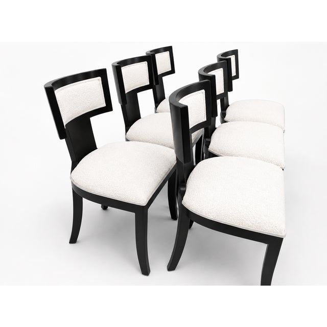 Modern set of Klismos style dining chairs. Chairs are done in a soho finish. The upholstery is white Boucle The Klismos...