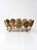 Vintage mid-century brass-plated wire fruit basket featuring sculptural spiral medallions and an open oval frame. The warm...