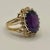This is part of Chairish’s Fine Jewelry assortment. 14k yellow gold cocktail ring featuring a deep purple/red/blue oval...
