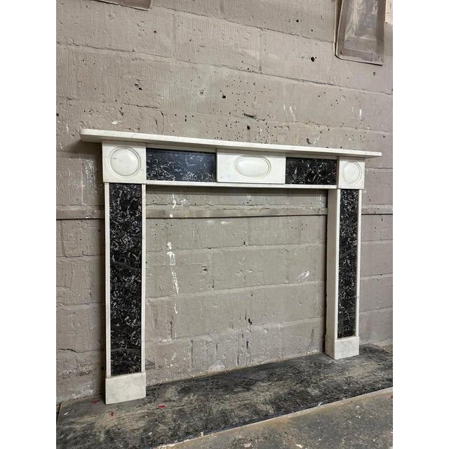 A very well drawn English Regency period 'Bulls Eye" fireplace in Statuary white and St Annes marble. The shelf, foot...