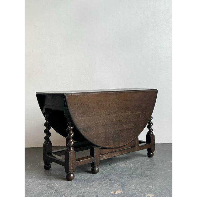 This exceptional vintage gateleg table is a masterclass in English Jacobean revival design, bringing architectural weight...