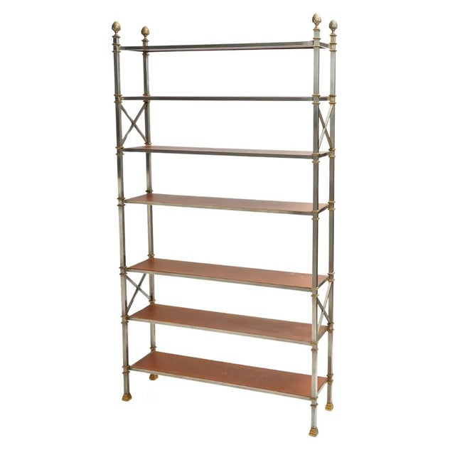 A pair of Maison Jansen brass and steel etageres with leather lined shelves. The seven shelf pair of etageres in a...