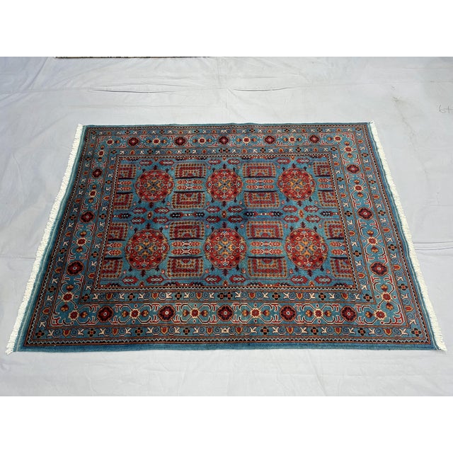 Bring rich color and intricate pattern to your home with this turquoise blue and red wool area rug. Six decorative red...