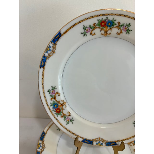 et of 6 hand-painted porcelain plates by Meito China, made in Japan and marked “Warren” on the base. A wide cream rim...