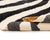 Abstract hand-knotted wool rug displaying Charcoal Black and Ivory zebra stripes with a central Gold Ochre swath that...