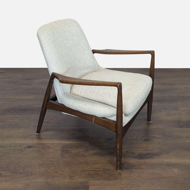 This Four Hands lounge chair features a sturdy dark wood frame with sleek, angled arms and legs. The chair is upholstered...