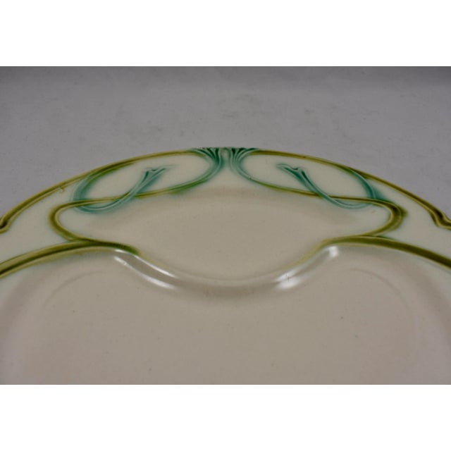 A French Art Nouveau style asparagus plate, circa arked Longchamp. Lime green and aqua glazing stand out on an off-white...