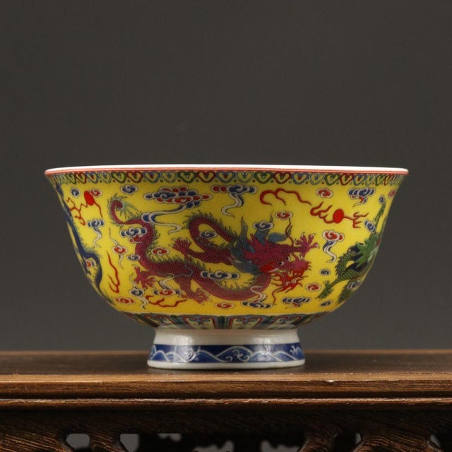 This elegant porcelain bowl features a striking bright yellow base, hand decorated with scrolling cloud motifs and...