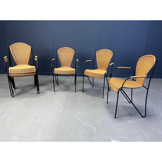 Vintage wrought iron and wicker bistro/dining chairs designed by Frederick Weinberg. Elegant black wrought frame with a...