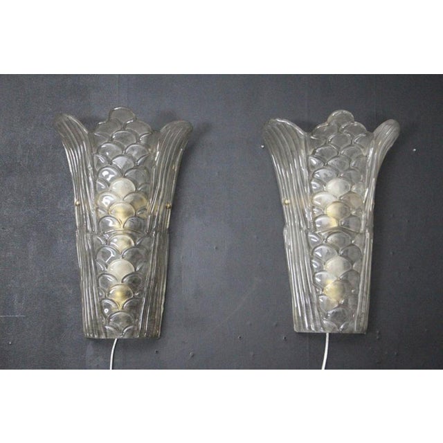 This pair of Art Deco wall sconces is in the style of « Muller Freres ». Made of molded, transparent and frosted Murano...