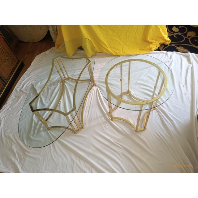 A set of two matching vintage solid polished brass and beveled glass top tables; one oval coffee and one side table....