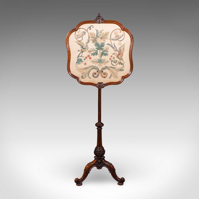 This is an antique pole screen. An English, rosewood and glass embroidered fireside heat reflector, dating to the early...