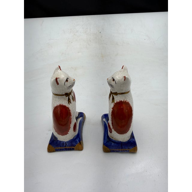 Pair of rare Staffordshire style ceramic cat figurines featuring a crackle glaze design. Decorated with red and white...