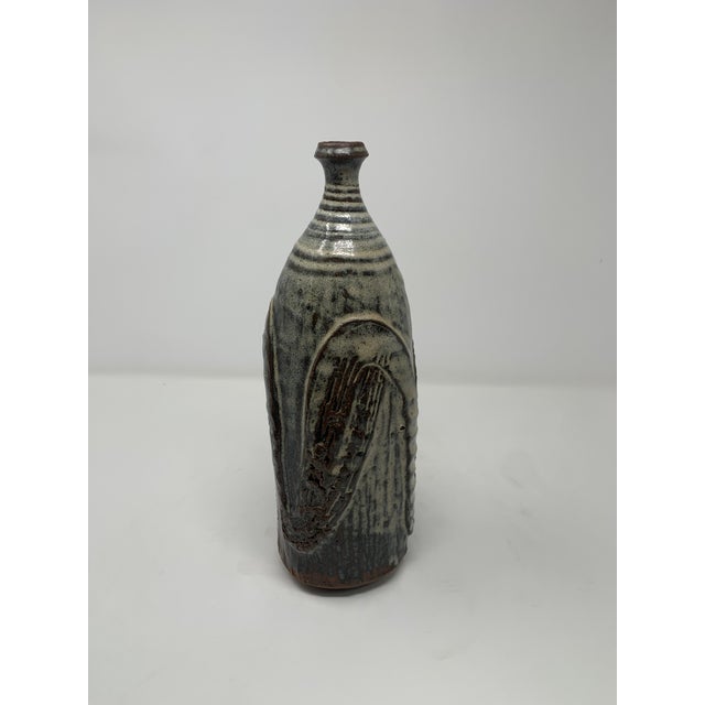 Unique mid-century ceramic vase with intricate carvings. A delicate white opaque glaze over a neutral base. Can be a...