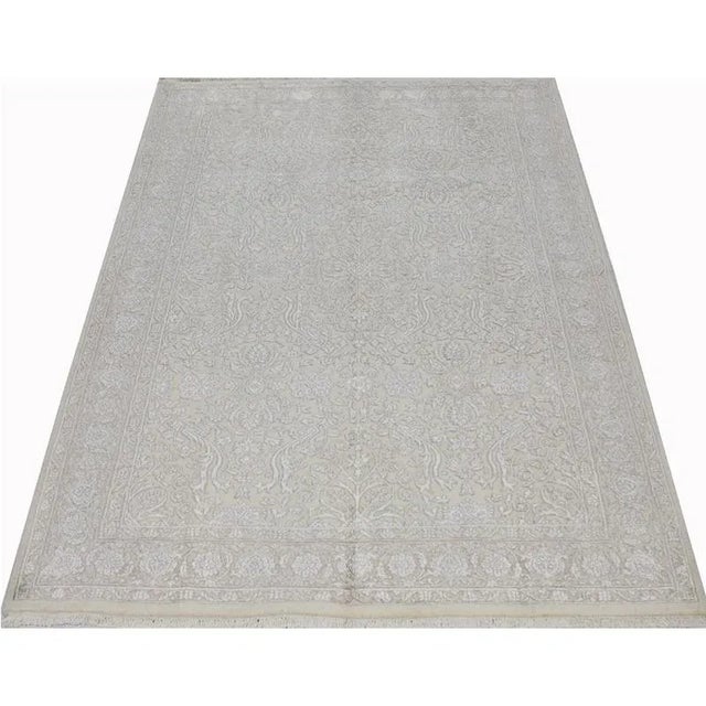 Traditional Handwoven Persian Style silk and wool Area Rug featuring an all-over design in a beige colored field enclosed...