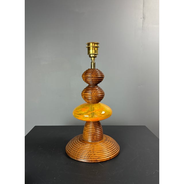 Lamp from the 1970s with a turned wooden base made of stacked, ribbed elements. The centre piece is a flattened disc of...