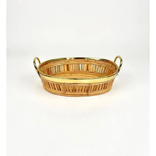 Oval centerpiece basket in rattan with handles featuring brass borders. Made in Italy in the 1970s.