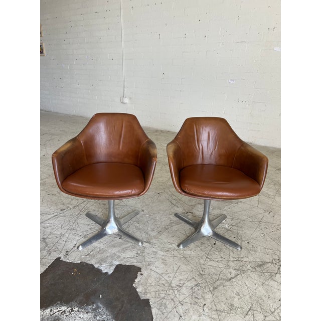 Pair of vintage leather tulip chairs by Burke, featuring leather with the perfect patina and swiveling chrome base. In...