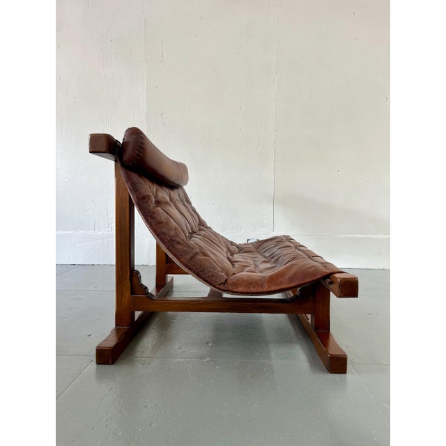 A heavy, sculptural sofa in the Brutalist tradition, with a solid wood frame that reads more like carved architecture than...
