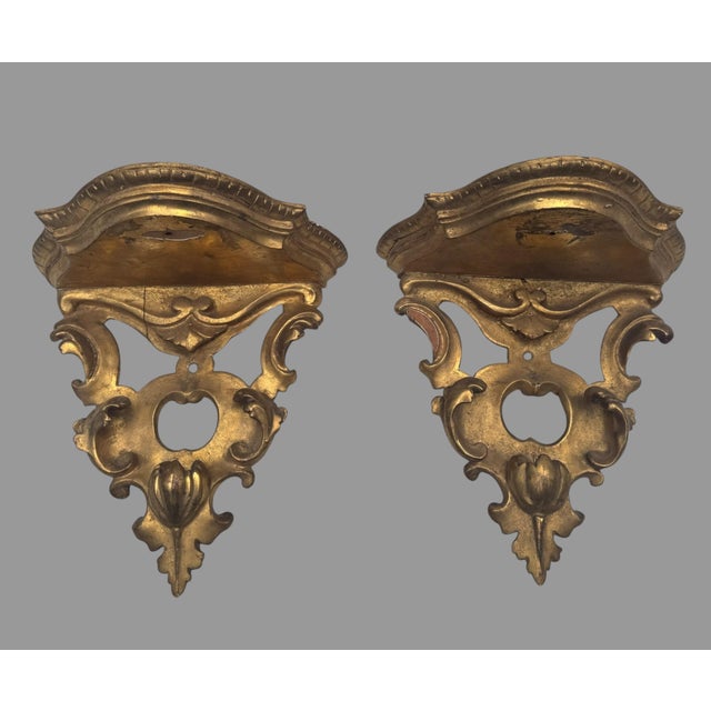 Beautiful antique pair of carved and giltwood wall bracket shelves featuring elaborate Rococo/Baroque-style scrollwork,...
