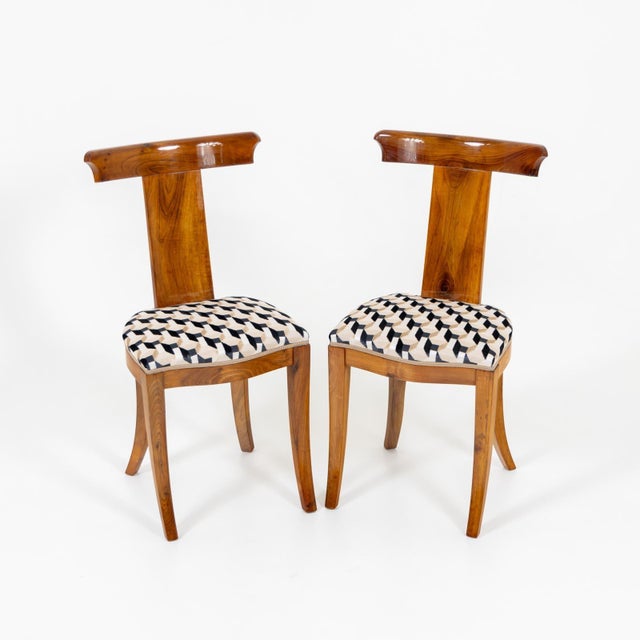 Set of five mid-century dining chairs with elegant t-shaped backrests and slightly flared legs. The chairs have been...