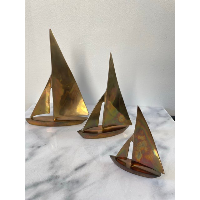 Charming collection of three brass sailboat figurines in graduated sizes. In great vintage condition with some areas of...