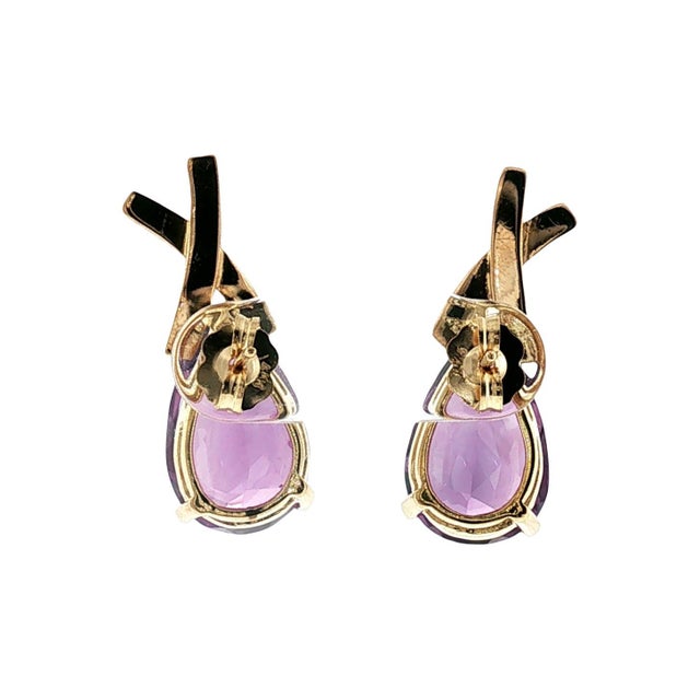 A pair of late 20th-century 14k yellow gold earrings featuring pear-cut amethyst stones. The gemstones are topped with a...