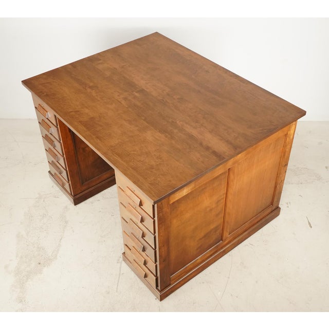 Early 20th century American Industrial style wooden desk. This desk is double sided with two workspaces, with twelve...