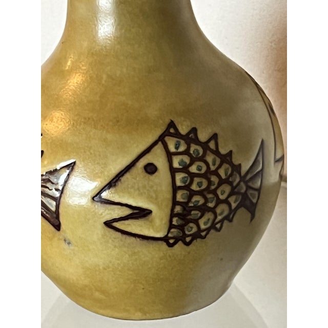 Small glazed ceramic lamp with a fish design, in perfect condition, signed with the monogram. Original raffia lampshade...