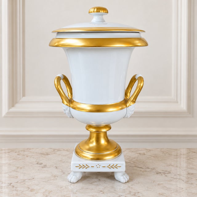 An elegant Belgian porcelain covered urn by Cerabel, Porcelaine de Baudour, featuring luminous white porcelain and rich...