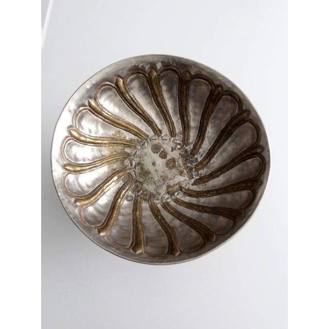 A mid-20th century pedestal bowl featuring a silver-toned exterior with warm brass accents. The softly scalloped form...