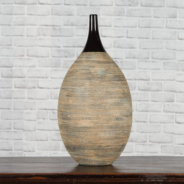A Thai Chiang Mai contemporary ceramic black neck vase from the Prem collection with textured belly. Charming our eye with...