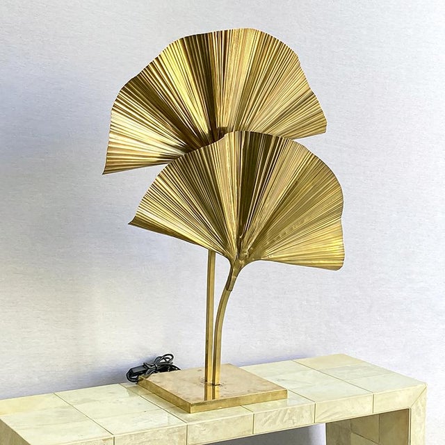 Entirely made of brass with a polished finish, this lamp with elegant curves and tropical charm is equipped with two...