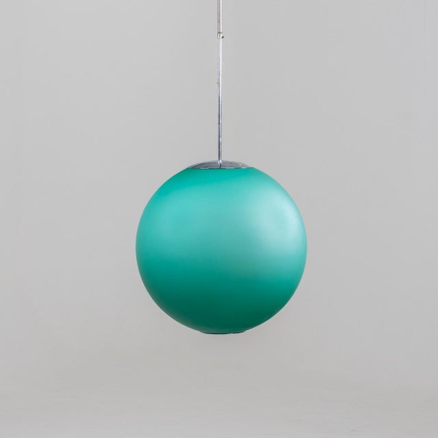 Large globe-shaped ceiling lamp made of turquoise glass on a long chromed rod. Label on the inside. This piece has an...