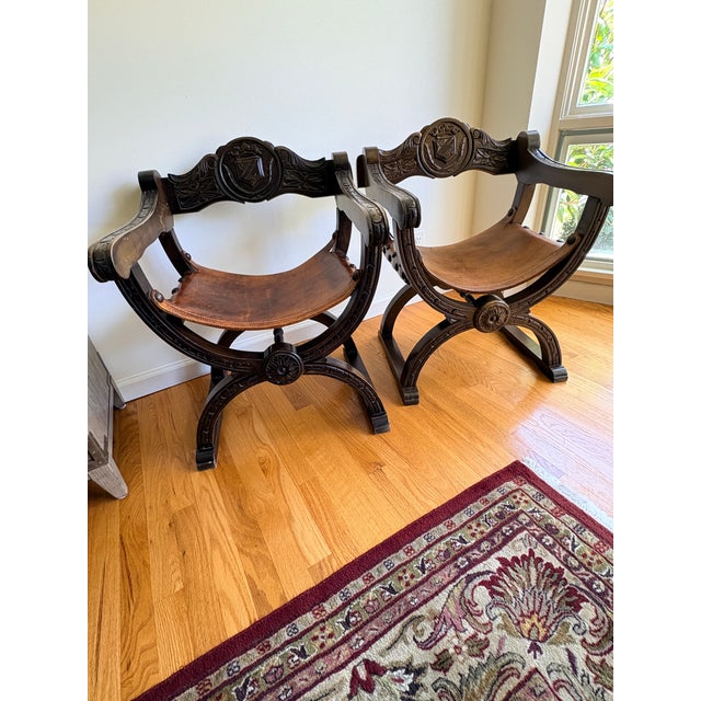 Vintage Renaissance Revival Savonarola Chair with Leather Sling Seat. Hand-carved solid wood frame featuring heraldic...