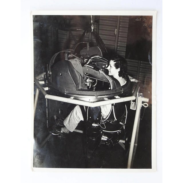 Circa 1940's silver gelatin official looking photograph of woman in the seat of a aircraft gun turret being assembled or...