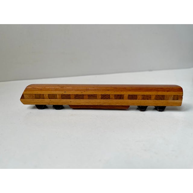 A rockets shaped corkscrew opener fashioned from solid teak a stainless steel. It is accompanied by a train shaped bottle...