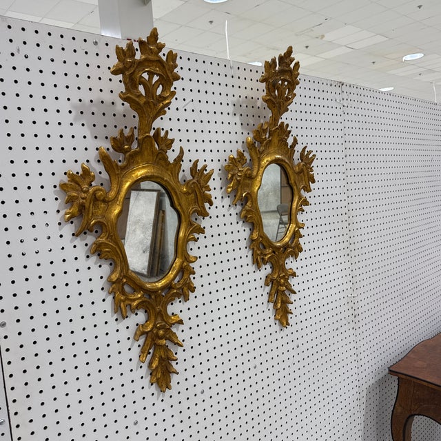 A striking pair of vintage mid-century Italian Florentine wall mirrors featuring an elongated vertical silhouette....